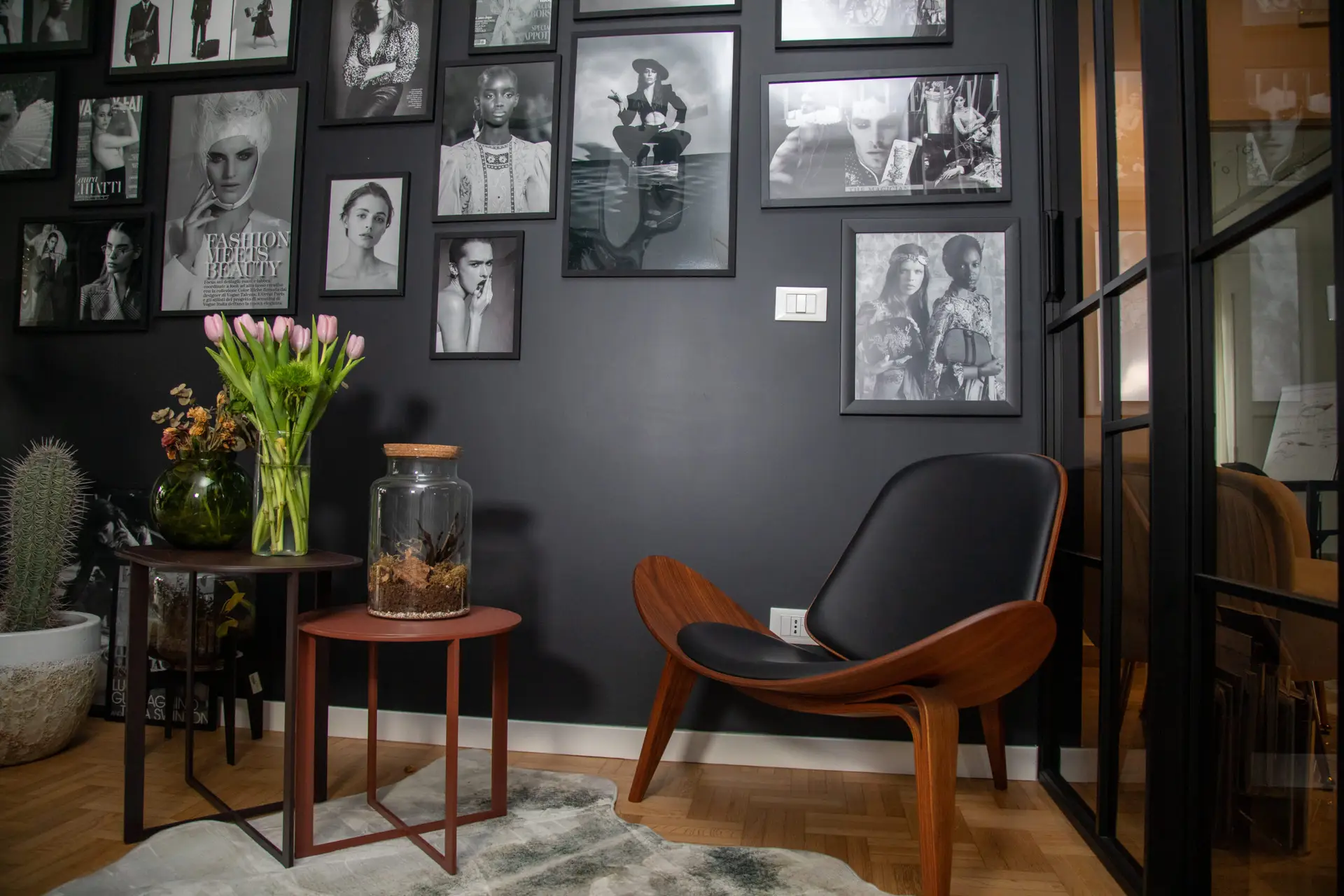 Angolo lounge di design di Ego Space con poltrona iconica, parete nera con foto editoriali di moda e vetrata artistica